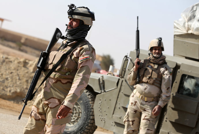 Iraqi soldiers stand along a road close to their vehicle in the area of Ein Tamer which leads west out of the central Iraqi Shiite Muslim shrine city of Karbala towards the mainly Sunni Muslim city of Fallujah, in the bordering Anbar province, on January 6, 2014. (AFP Photo)