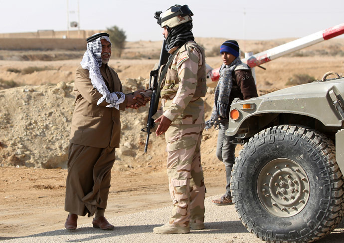 A Sunni Muslim Iraqi man shakes the hand of a soldier at Ein Tamer as families flee their homes in the city of Fallujah making their way to the central Iraqi Shiite Muslim shrine city of Karbala, on January 6, 2014. (AFP Photo)
