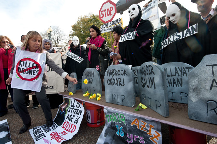 Medea Benjamin (L), co-founder of the anti-war group CodePink, places flowers on mock graves of drone victims in Afghanistan, Pakistan and Yemen, in front of the White House in Washington on November 15, 2013 ahead of the Global Drone Summit. (AFP Photo)