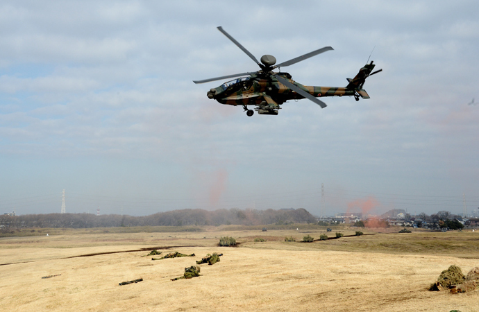 Japanese Ground Self Defense forces' AH-1 helicopter flies over military vehicles and personnels during the new year exercise in Narashino in Chiba prefecture, suburban Tokyo on January 12, 2014 (AFP Photo / Yoshikazu Tsuno)