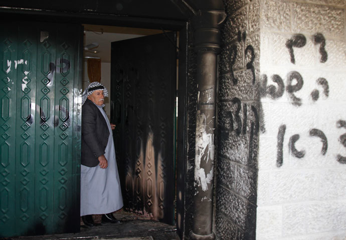 A Palestinian man stands near a door and wall of a mosque which were vandalised in the West Bank village of Deir Istiya, near the Jewish settlement of Ariel January 15, 2014.(Reuters / Abed Omar Qusini )
