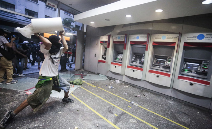 A demonstrator attacks a bank branch during the "Nao Vai Ter Copa" (You are not going to have Cup) protest along Consolacao Street, in Sao Paulo, Brazil, on January 25, 2014. (AFP Photo/Miguel Schincariol)