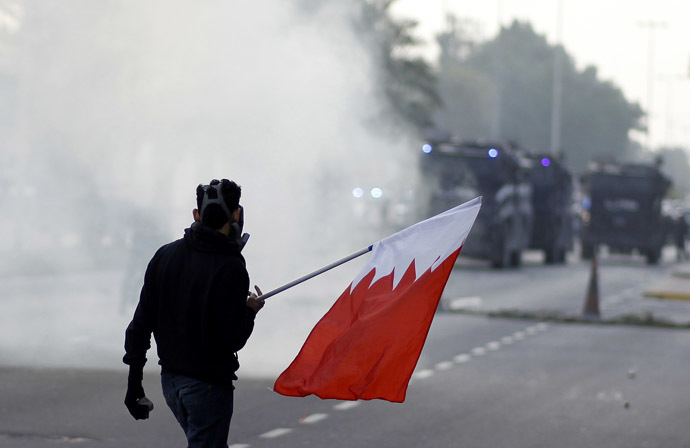 An anti-government protester holds a Bahraini flag during clashes with riot police after the funeral procession of Fadhel Abas Muslim in the village of Diraz, west of Manama, January 26, 2014. (Reuters/Hamad I Mohammed)