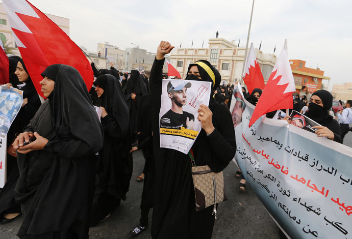Anti-government protesters hold placards with images of Fadhel Abas Muslim, as they shout anti-government slogans while marching during his funeral in the village of Diraz, west of Manama, January 26, 2014. (Reuters/Hamad I Mohammed)