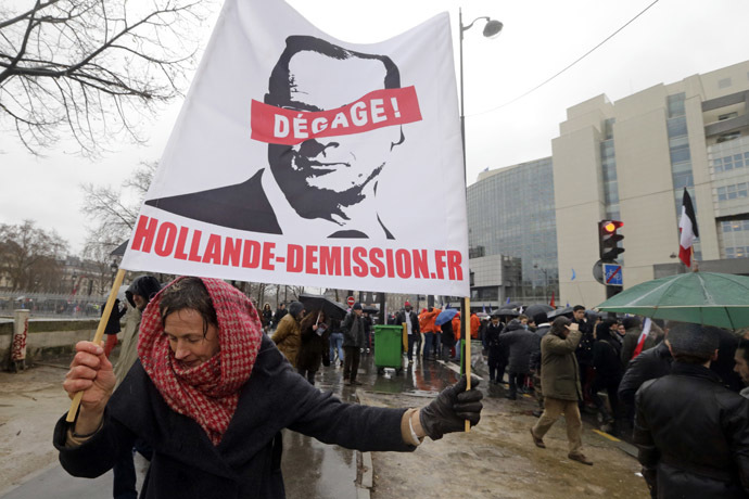 A demonstrator holds a banner which reads, "Hollande Resign" as several thousand people attend the "Journee de la Colere" (Day of Anger) march in protest of France's President Francois Hollande, in Paris January 26, 2014. (Reuters/Philippe Wojazer)