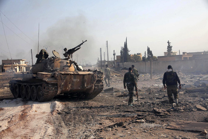 Forces loyal to Syria's President Bashar al-Assad hold their weapon as they stand near a tank in Tel Hasel, Aleppo province after capturing it from rebels (Reuters/George Ourfalian)