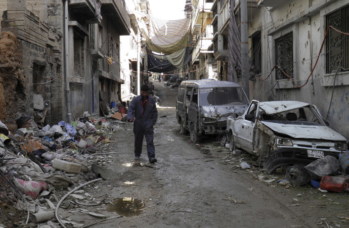 A man walks along a street past damaged buildings and vehicles in the besieged area of Homs January 28, 2014. (Reuters/Thaer Al Khalidiya)