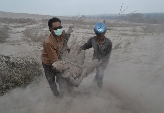  Indonesian residents rescue a victim following eruptions of Mount Sinabung in Karo district, North Sumatra province, on February 1, 2014. (AFP Photo)