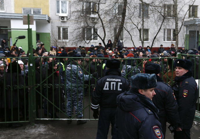 Interior Ministry members stand guard as bystanders and relatives of students gather behind a fence near a high school, where a student shot a teacher and a police officer dead and held more than 20 other students hostage, on the outskirts of Moscow, February 3, 2014. (Reuters/Maxim Shemetov)
