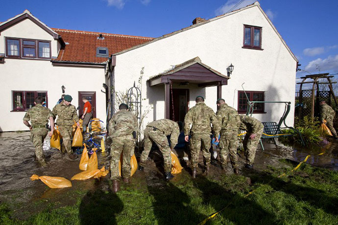 British Royal Marines help lay sandbags around a home threatened by floodwaters during flood relief operations in Moorland, some 19 Kms Northeast of Taunton on February 7, 2014. (AFP Photo / Justin Tallis)