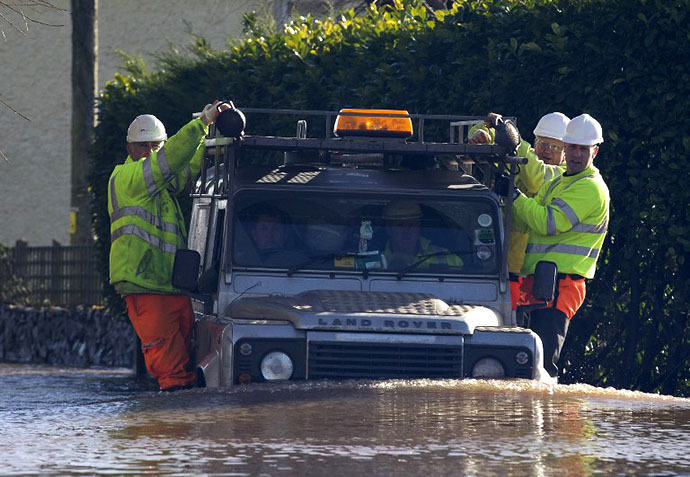 Environment agency workers take a ride on the side of a Land Rover as they travel through flood waters in Moorland, 19 Kms northeast of Taunton on February 7, 2014. (AFP Photo / Justin Tallis)