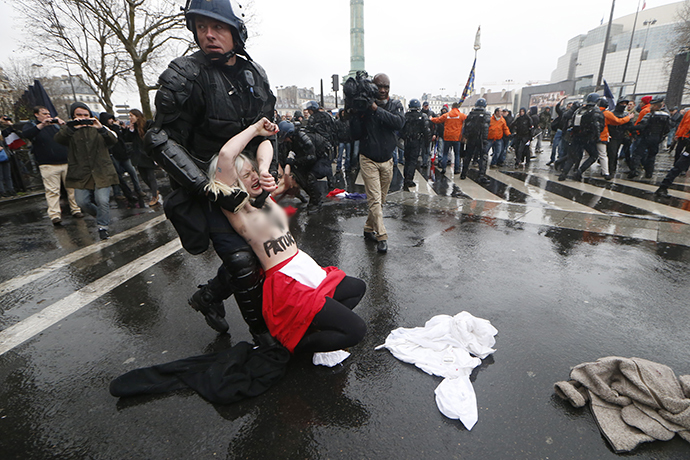 (ARCHIVE PHOTO) A gendarme holds a member of the Femen feminist activist group as Femens protest against a demonstration organized against the French government and the French President on January 26, 2014, in Paris (AFP Photo / Thomas Samson)
