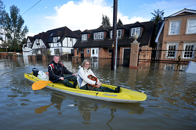 Residents paddle through floodwater in the village of Wraysbury in Berkshire, South East England, on February 10, 2014. (AFP Photo / Ben Stansall)