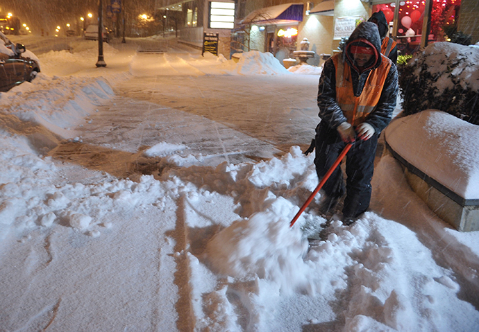 A worker clears snow from a sidewalk in Chevy Chase, Maryland, in the early hours of February 13, 2014. (AFP Photo / Mandel Ngan)