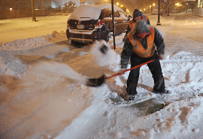 A worker clears snow from a sidewalk in Chevy Chase, Maryland, in the early hours of February 13, 2014. (AFP Photo / Mandel Ngan)