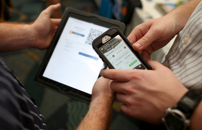 Eric Martindale (L) and John Dreyzehner from BitPay, the world leader in Bitcoin business solutions, demonstrate a transaction using an ipad to charge a customer who is using his phone to transfer Bitcoins for the purchase (AFP Photo / Joe Raedle)