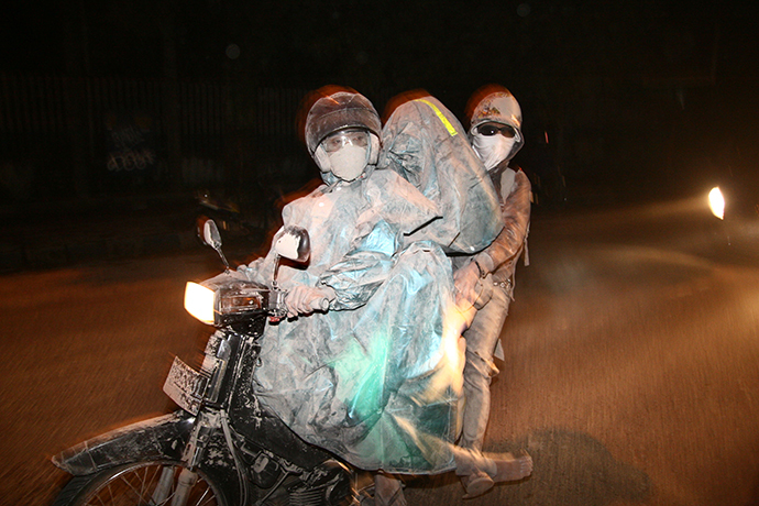 Residents evacuate to a safe place by riding a motorbike in Malang, East Java province, on February 14, 2014 moment after Mount Kelud erupted. (AFP Photo / Aman Rochman)