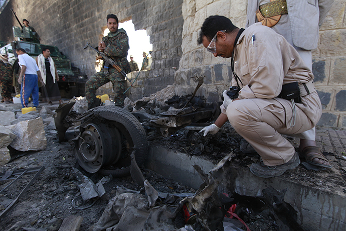 Investigators from the criminal investigation department (CID) examine the wreckage of a car after a bomb exploded outside the main wall outside the central prison in Sanaa February 14, 2014. (Reuters / Mohamed Al-Sayaghi)