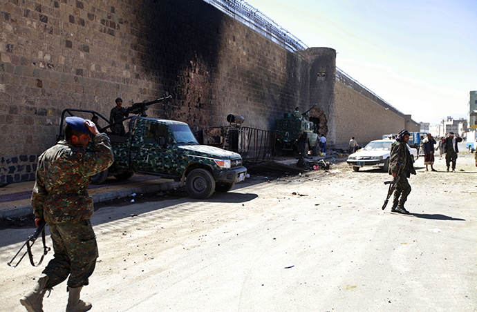 Policemen stand guard next to a wall of the central prison in Sanaa after a bomb exploded outside, February 14, 2014. (Reuters / Mohamed Al-Sayaghi)