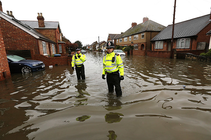 Police officers walk down a street in Egham after the River Thames burst its banks in southeast England February 14, 2014. (Reuters / Paul Hackett)