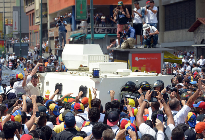 Supporters of Leopoldo Lopez, an ardent opponent of Venezuela's socialist government facing an arrest warrant after President Nicolas Maduro ordered his arrest on charges of homicide and inciting violence, surround the National Guard vehicle driving Lopez away after he turned himself in during a demonstration in Caracas on February 18, 2014. (AFP Photo / Raul Arboleda) 