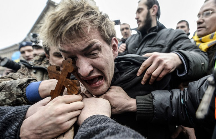 An alleged sniper and member of the pro-government forces is beaten by anti-government protestors in Kiev on February 22, 2014. (AFP Photo / Bulent Kilic)