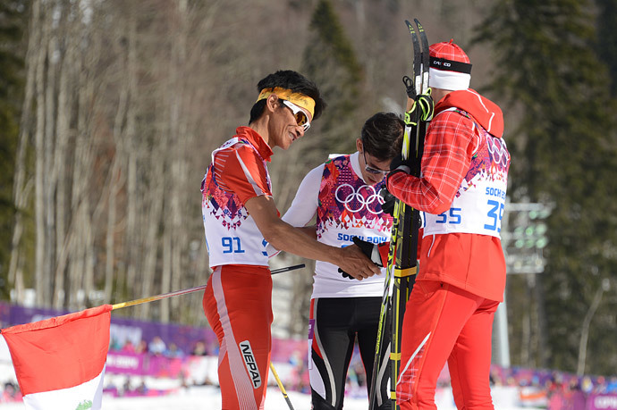 Peru's Roberto Carcelen (C) and by Nepal's Dachhiri Sherpa (L) are congratulated by gold winner Switzerland's Dario Cologna (R) after crossing the finish line in the Men's Cross-Country Skiing 15km Classic at the Laura Cross-Country Ski and Biathlon Center during the Sochi Winter Olympics on February 14, 2014. (AFP Photo / Kirill Kudryavtsev)