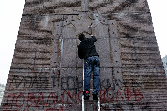 An anti-Yanukovich protester attempts to demolish the "Monument to Soviet secret security service (chekists) - fighters of the revolution" in Kiev February 23, 2014 (Reuters / Konstantin Chernichkin)