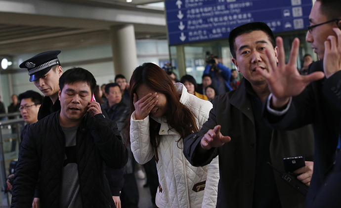 A woman (C), believed to be the relative of a passenger onboard Malaysia Airlines flight MH370, covers her face as she cries at the Beijing Capital International Airport in Beijing March 8, 2014. (Reuters / Kim Kyung Hoon)