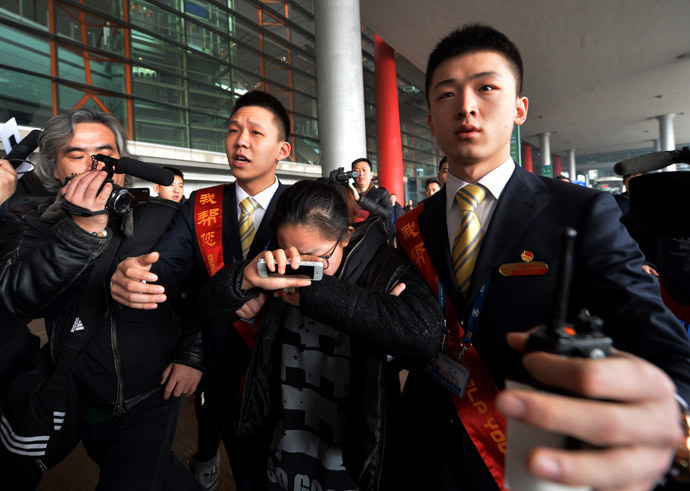A crying woman is escorted to a bus for relatives at the Beijing Airport after news of the missing Malaysia Airlines Boeing 777-200 plane on March 8, 2014.(AFP Photo / Mark Ralston)