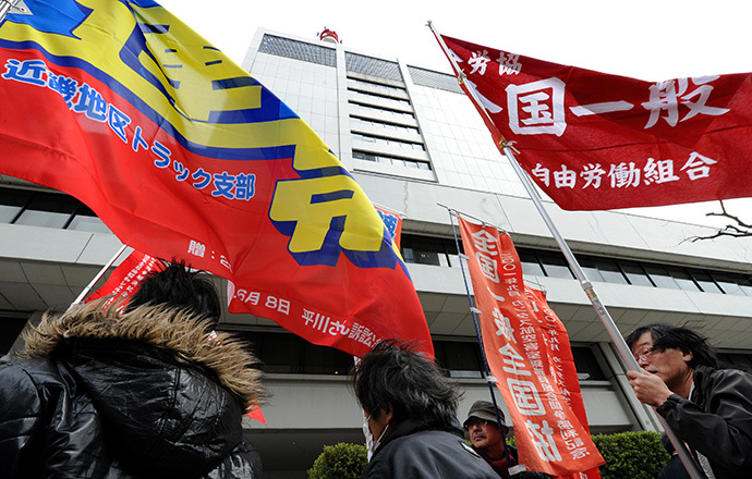Fukushima nuclear power workers and their supporters hold flags in front of the headquarters of Tokyo Electric Power Company (TEPCO), operator of the tsunami-battered Fukushima Daiichi nuclear power plant, during a rally in Tokyo on March 14, 2014 (AFP Photo / Toru Yamanaka)