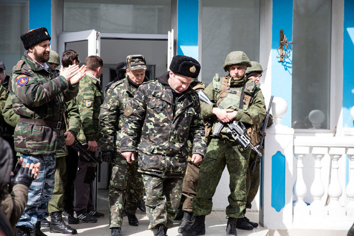 Ukrainian servicemen pass by armed men while leaving the territory of the naval headquarters in Sevastopol, March 19, 2014. (Reuters / Baz Ratner)