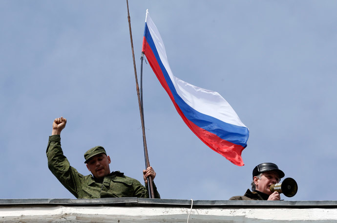 A man holds a Russian flag on the roof of the naval headquarters in Sevastopol, March 19, 2014. (Reuters / Vasily Fedosenko)