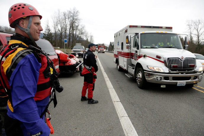 Members of a swift water rescue team look on as an ambulance drives past after a large mudslide blocked Highway 530 near Oso, Washington March 22, 2014. (Reuters / Jason Redmond)
