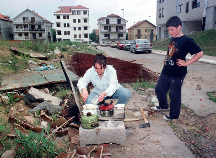 A boy watches his mother prepare food in Belgrade May 23. (Reuters)