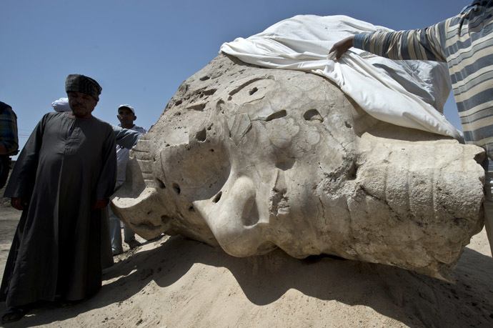 Egyptian archaeological workers stand next to a newly displayed alabaster head from an Amenhotep III statue in Egypt's temple city of Luxor on March 23, 2014. (AFP Photo)