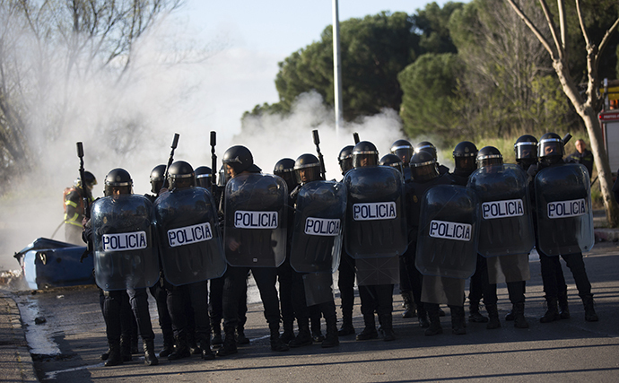 Riot police officers stand beside a barricade with their shields at Complutense University on the second day of a 48-hour student strike to protest against rising fees and educational cuts in Madrid March 27, 2014. (Reuters / Andrea Comas)