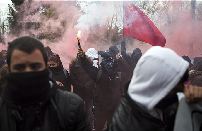 A student raises a flare during a protest at Complutense University on the second day of a 48-hour student strike to protest against rising fees and educational cuts in Madrid March 27, 2014. (Reuters / Andrea Comas)