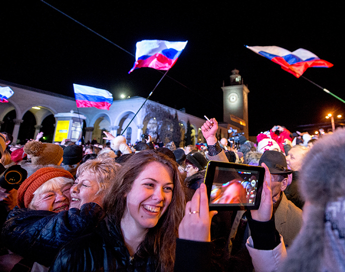 People celebrate the transition to Moscow time near a city clock tower at a railway station in Simferopol on March 30, 2014. (AFP Photo / Dmitry Serebryakov)