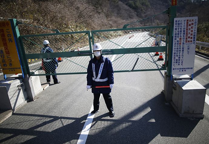 Security personnel stand guard near a steel gate that marks the border between Tamura and Okuma town in Okuma town, Fukushima prefecture April 1, 2014. (Reuters / Issei Kato)