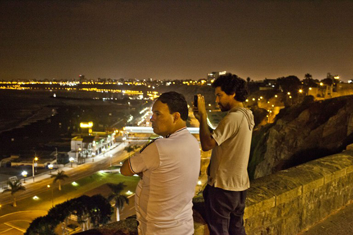 People survey the "Costa Verde" bay from atop a hill following a tsunami alert in Lima on April 1, 2014. (AFP Photo / Ernesto Benavides)