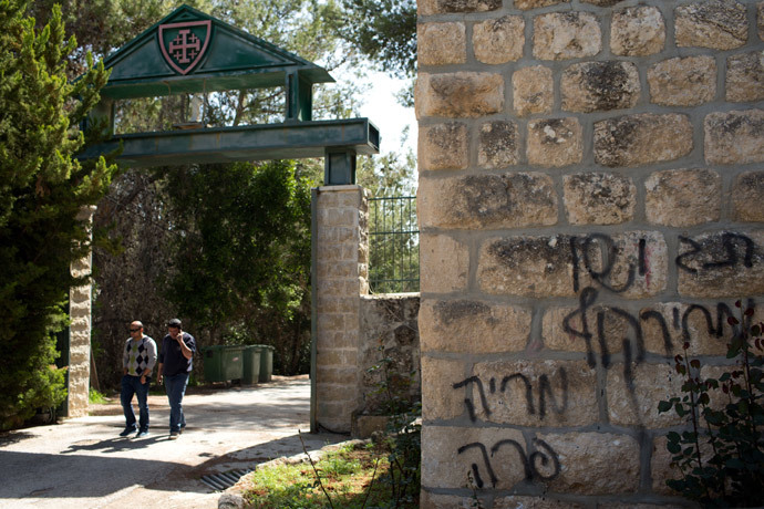 People leave the Deir Rafat Catholic convent whose walls were sprayed with a graffiti (R) reading in Hebrew "Jesus monkey, Maria cow, Tag price" on April 1, 2014 near the Israeli city of Beit Shemesh, west of Jerusalem. (AFP Photo / Menahev Kahana)