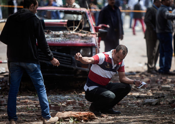 A member of the Egyptian security personnel inspects the scene after twin bombs struck police posts near Cairo University in the centre of Egypt's capital on April 2, 2014. (AFP Photo / Mahmoud Khaled) 