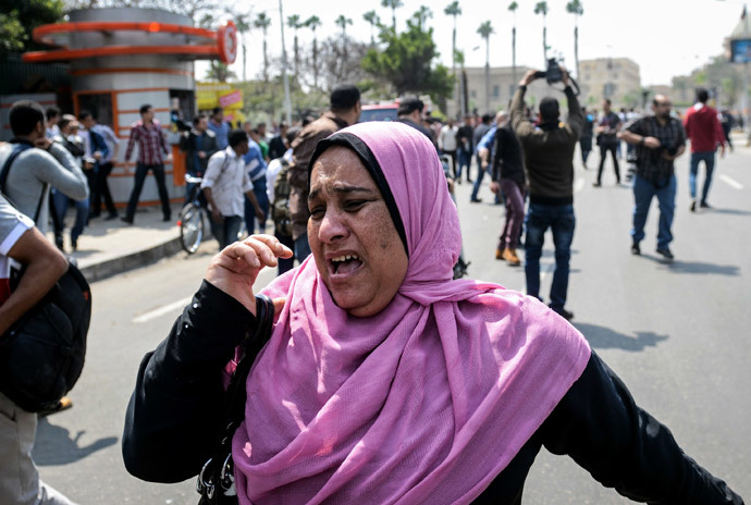 An Egyptian woman runs for cover as a bomb struck a police post near Cairo University in the centre of Egypt's capital on April 2, 2014. (AFP Photo / Mohamed El-Shahed)