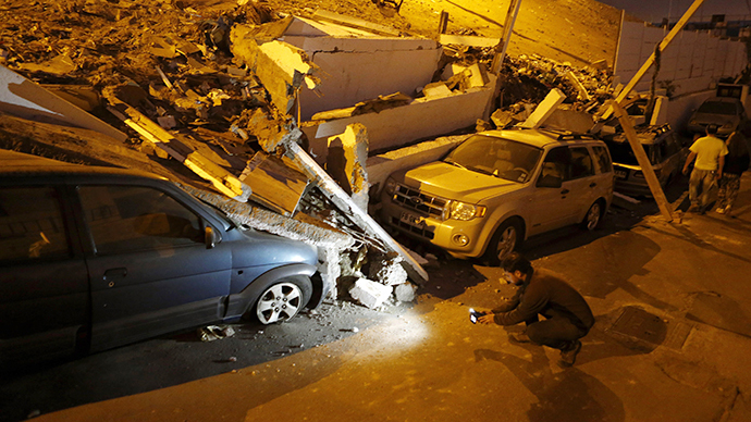 A cameraman records near cars caught under rubble after an earthquake and tsunami hit the northern port of Iquique April 2, 2014. (Reuters / Ivan Alvarado)