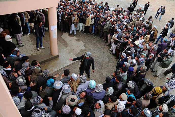 An Afghan policeman tries to keep order as voters wait in line outside a polling station inBamiyan on April 5, 2014. (AFP Photo / Shefayee)