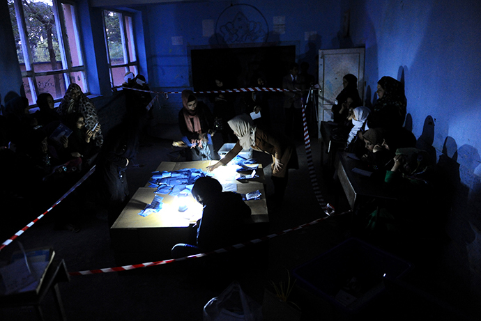 Afghan election workers sort presidential ballots by the light of a lantern after a polling station was closed for voting in the northwestern city of Herat on April 5, 2014. (AFP Photo / Aref Karimi)