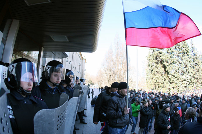 A man holds a Russian flag as police officers stand guard outside the regional government administration building in the center of the eastern Ukrainian city of Donetsk during a rally of pro-Russia supporters on April 5, 2014. (AFP Photo)