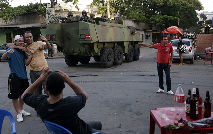 Residents take pictures in front of Brazilian Navy soldiers in an armoured vehicle during an operation in the Mare slums complex in Rio de Janeiro, April 5, 2014. (Reuters / Ricardo Moraes)
