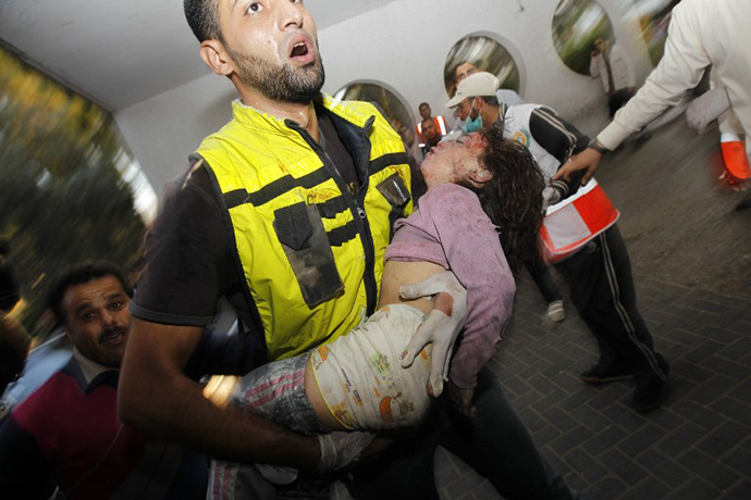 A Palestinian rescue worker carries the body of a child from the al-Dallu family into the hospital in Gaza City on November 18, 2012, after seven members of the al-Dallu family, including four children, were among nine people killed when an Israeli missile struck a family home in Gaza City, the health ministry said. (AFP Photo / Mohammed Abed)